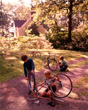 simsearch:846-05646643,k - 1970s 3 BOYS BACKYARD DRIVEWAY SUBURBAN HOUSE WORK ON BICYCLE MAINTENANCE REPAIR Foto de stock - Direito Controlado, Número: 846-05647162