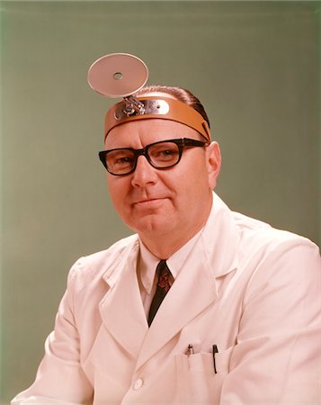 retro glasses - 1950s - 1960s SMILING MAN MEDICAL DOCTOR WHITE LAB COAT BLACK FRAME EYEGLASSES WEARING DIAGNOSTIC HEAD MIRROR ON FOREHEAD Stock Photo - Rights-Managed, Code: 846-05647200