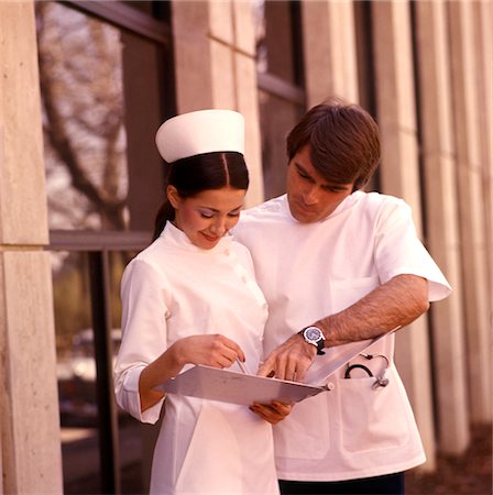 simsearch:846-02794586,k - 1970s DOCTOR INTERN LOOK AT CHART WITH NURSE WEARING NURSES CAP Foto de stock - Con derechos protegidos, Código: 846-05647246