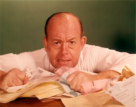 executive looking at camera on desk - 1960s ANGRY MAN BUSINESSMAN DESK FULL OF BILLS PAPER WORK OFFICE STRESS FRUSTRATION Stock Photo - Rights-Managed, Code: 846-05647282