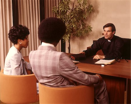 simsearch:846-07760753,k - 1970s PRIEST MINISTER CLERGY MAN INTERVIEWING CONSULTING AFRICAN AMERICAN COUPLE MAN WOMAN Stock Photo - Rights-Managed, Code: 846-05647360