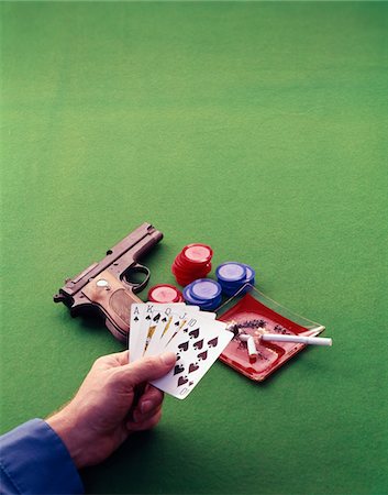 person hand on gun - 1970s MAN HAND HOLDING ROYAL STRAIGHT FLUSH IN SPADES PLAYING CARDS ON GREEN FELT CARD TABLE POKER CHIPS CIGARETTE ASH TRAY PISTOL Stock Photo - Rights-Managed, Code: 846-05647393