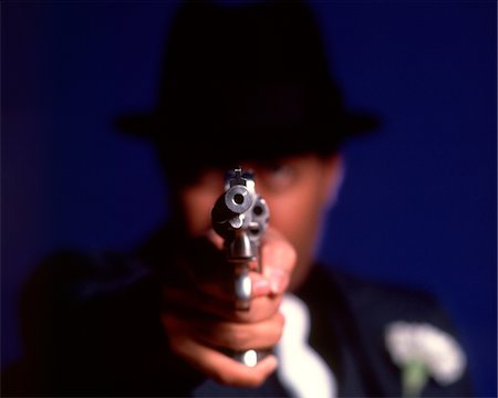 1970s BLURRY OUT OF FOCUS MAN CRIMINAL GANGSTER POINTING BARREL GUN DIRECTLY TOWARD LENS Foto de stock - Con derechos protegidos, Código: 846-05647420