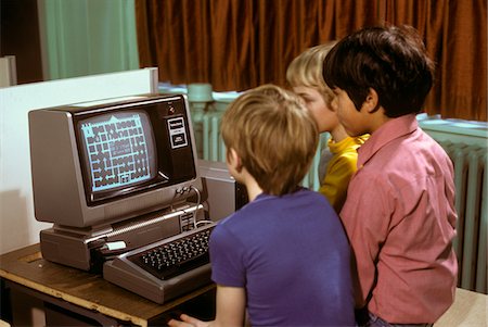 década de 1980 - 1980s 3 ELEMENTARY SCHOOL BOYS OPERATING EARLY RADIO SHACK TRS80 COMPUTER PLAYING GAME Foto de stock - Direito Controlado, Número: 846-05647435