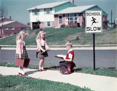 simsearch:846-02797431,k - 1950s TWO TWIN BLOND GIRLS ONE BLOND BOY ON SIDEWALK BY SCHOOL SLOW SIGN IN NEIGHBORHOOD OF SUBURBAN SPLIT LEVEL HOUSES Stock Photo - Rights-Managed, Code: 846-05647485