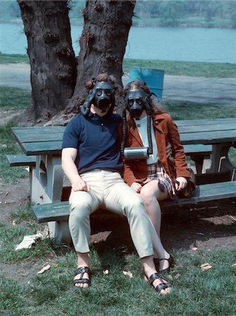 simsearch:846-02797081,k - ANNÉES 1970 JEUNE COUPLE ASSIS SUR BANC DE PARC PORTANT DES MASQUES À GAZ Photographie de stock - Rights-Managed, Code: 846-05647500