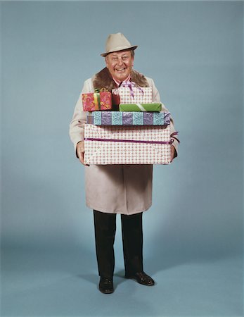 ANNÉES 1950 MANTEAU CHAPEAU HOMME SOURIANT TRANSPORTANT ENVELOPPÉ DE CADEAUX DE NOËL Photographie de stock - Rights-Managed, Code: 846-05647608