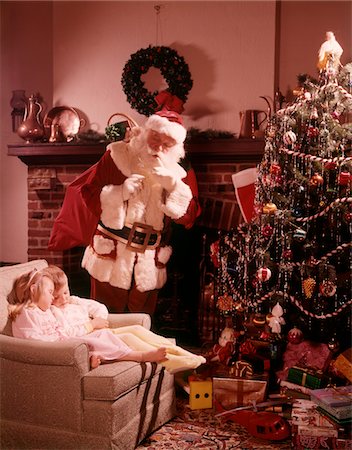 1960s SANTA LOOKING DOWN ON TWO CHILDREN BOY GIRL ASLEEP IN CHAIR BY FIREPLACE CHRISTMAS TREE Foto de stock - Con derechos protegidos, Código: 846-05647602