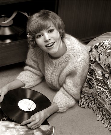 ANNÉES 1960 SOURIANTE JEUNE FEMME PULL SITUÉE À L'ÉTAGE CHAMBRE ÉCOUTER DE LA MUSIQUE SUR VINYL RECORD ALBUM Photographie de stock - Rights-Managed, Code: 846-05647681