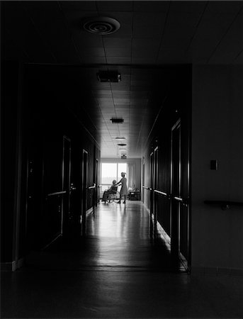 ANNÉES 1960 - ANNÉES 1970 INFIRMIÈRE POUSSANT PERSONNES ÂGÉES FEMELLE PATIENT DOWN DARK HÔPITAL COULOIR EN FAUTEUIL Photographie de stock - Rights-Managed, Code: 846-05647713