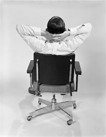 simsearch:846-02796052,k - 1960s MAN FROM BEHIND SITTING IN OFFICE EXECUTIVE CHAIR HANDS CLASPED BEHIND NECK Stock Photo - Rights-Managed, Code: 846-05647756
