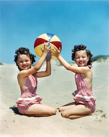 family playing with beach ball - 1940s - 1950s SMILING TWIN GIRLS WEARING CHECKERED BATHING SUITS AT BEACH HOLDING BEACH BALL Stock Photo - Rights-Managed, Code: 846-05647833