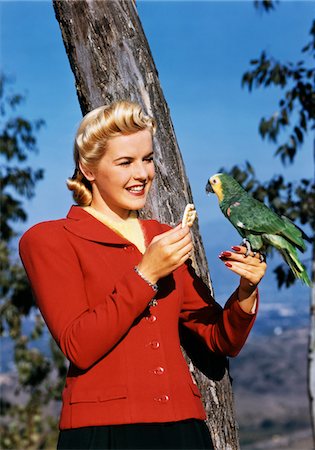 fütterung - 1940ER JAHRE BLONDE FRAU LÄCHELND FÜTTERUNG CRACKER PARROT IM FREIEN Stockbilder - Lizenzpflichtiges, Bildnummer: 846-05647865