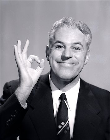 1950s PORTRAIT OF HAPPY SMILING MAN BUSINESSMAN SALESMAN MAKING AN OK HAND SIGN Foto de stock - Direito Controlado, Número: 846-05647898