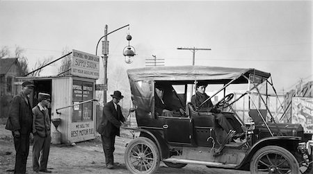 1910s KANSAS CITY MISSOURI MAN FILLING TANK OF OLD CAR AT GASOLINE STATION NEXT TO THE OLD SANTA FE TRAIL Foto de stock - Con derechos protegidos, Código: 846-05647958