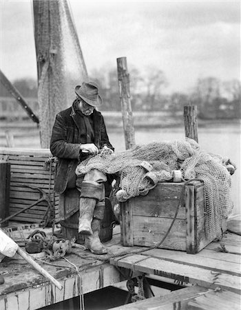 ANNÉES 1910 VIEUX HOMME PÊCHEUR RÉPARER LES FILETS DE PÊCHE SUR LE QUAI WESTPORT CONNECTICUT Photographie de stock - Rights-Managed, Code: 846-05647964