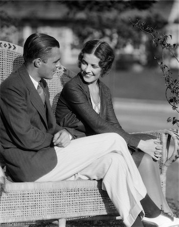 simsearch:846-02794951,k - 1930s SMILING COUPLE SITTING TOGETHER ON WICKER BENCH HUSBAND WIFE OUTDOOR Stock Photo - Rights-Managed, Code: 846-05648082