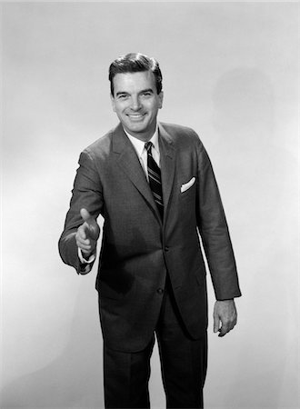 1960s SMILING SALESMAN OR BUSINESSMAN LEANING FORWARD EXTENDING HAND FOR HANDSHAKE Stock Photo - Rights-Managed, Code: 846-05648102