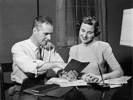 1950s COUPLE MAN WOMAN SMILING LOOKING AT BANKING SAVINGS PASSBOOK AT HOME DESK Stock Photo - Rights-Managed, Code: 846-05648214
