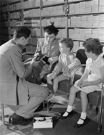 1950s FAMILY MOTHER TWO CHILDREN IN SHOE STORE TRYING NEW SHOES HELPED BY SALESMAN Foto de stock - Con derechos protegidos, Código: 846-05648257