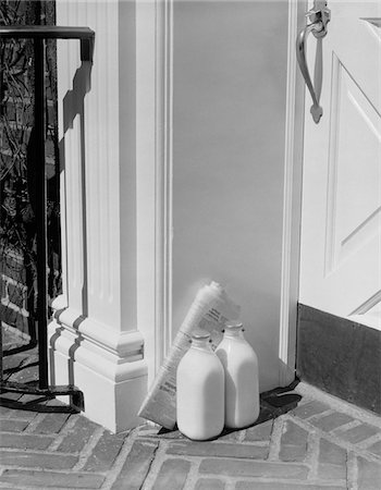 BOUTEILLES DE VERRE DE LAIT DES ANNÉES 1950 ET DANS LES JOURNAUX DE LIVRAISON À DOMICILE DE PORTE AVANT Photographie de stock - Rights-Managed, Code: 846-05648354