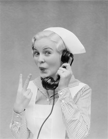 1930s SMILING BLOND NURSE WITH SURPRISED EXPRESSION TALKING ON TELEPHONE HOLDING UP TWO FINGERS Stock Photo - Rights-Managed, Code: 846-05648471