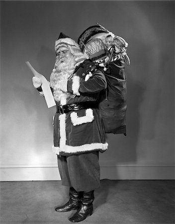 simsearch:846-09013030,k - 1940s SANTA CLAUS CARRYING BAG FULL OF TOYS READING LIST Stock Photo - Rights-Managed, Code: 846-05648528