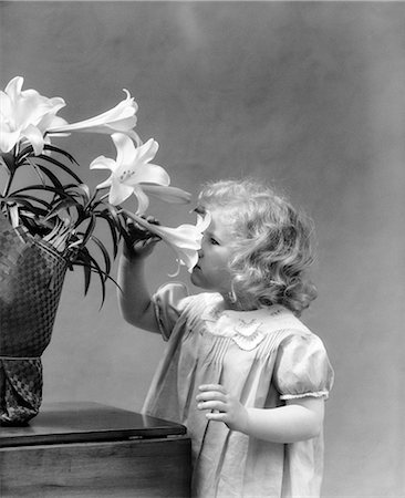 simsearch:846-03164419,k - 1940s LITTLE BLOND GIRL SMELLING EASTER LILY Stock Photo - Rights-Managed, Code: 846-06111775