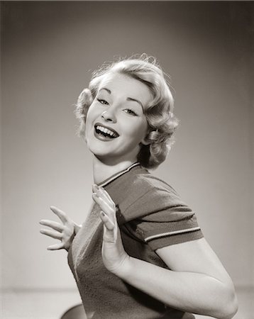 1950s YOUNG WOMAN SMILING WITH BOTH THUMBS TUCKED UNDER HER ARM LOOKING AT CAMERA Foto de stock - Con derechos protegidos, Código: 846-06111847