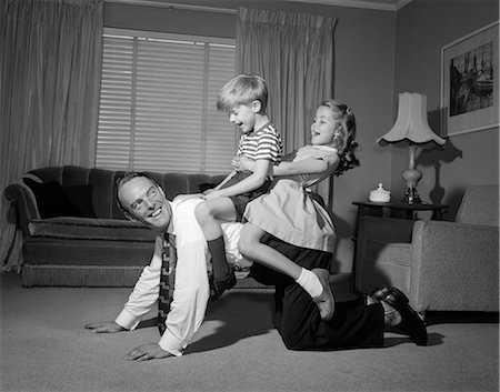 simsearch:846-08512733,k - 1950s 1960s DAD CARRYING BOY & GIRL PIGGYBACK ON LIVING ROOM FLOOR Stock Photo - Rights-Managed, Code: 846-06111942
