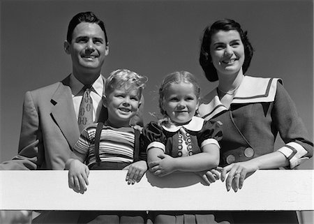 simsearch:846-05646502,k - 1950s PORTRAIT SMILING FAMILY FATHER MOTHER DAUGHTER SON STANDING TOGETHER BEHIND WHITE FENCE OUTDOOR Stock Photo - Rights-Managed, Code: 846-06111957