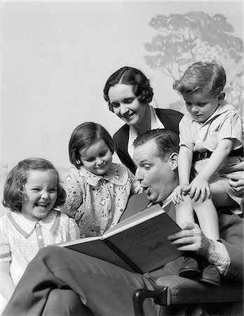 simsearch:846-02795857,k - 1930s FAMILY OF FIVE GROUPED AROUND FATHER READING CHILDREN'S PUNCH BOOK Foto de stock - Con derechos protegidos, Código: 846-06111951