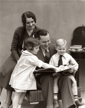 retro friendship - LIVRE DE LECTURE POUR FILLE FILS & AVEC MÈRE REGARDANT PAR DESSUS SON ÉPAULE LE PÈRE DES ANNÉES 1930 Photographie de stock - Rights-Managed, Code: 846-06111963