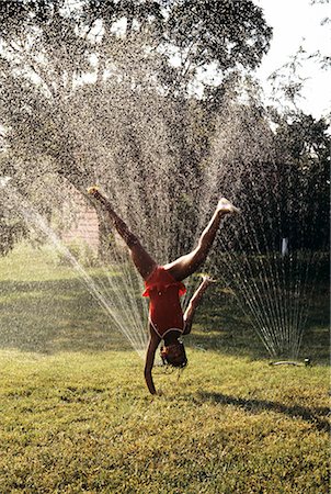 suburban backyard - LITTLE GIRL CARTWHEELING THROUGH LAWN SPRINKLER Stock Photo - Rights-Managed, Code: 846-06112076