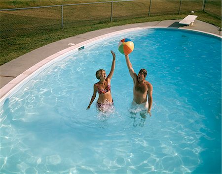 stylish swimming pool - 1980 1980s MAN WOMAN COUPLE JUMPING UP BEACH BALL BACKYARD SWIMMING POOL MEN WOMEN COUPLES SWIM POOLS FUN SUMMER Stock Photo - Rights-Managed, Code: 846-06112106