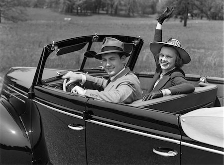 simsearch:846-07200077,k - 1930s COUPLE IN CONVERTIBLE WEARING HATS WITH GLOVED WOMAN WAVING AT CAMERA SMILING LOOKING AT CAMERA Stock Photo - Rights-Managed, Code: 846-06112139