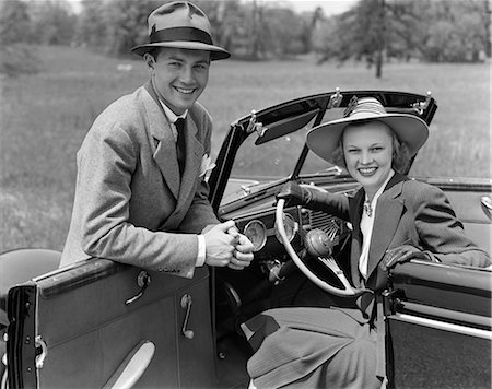 simsearch:846-02795490,k - 1930s 1940s PORTRAIT COUPLE MAN WOMAN TOGETHER WITH CONVERTIBLE AUTOMOBILE SMILING WEARING HATS LOOKING AT CAMERA Fotografie stock - Rights-Managed, Codice: 846-06112141