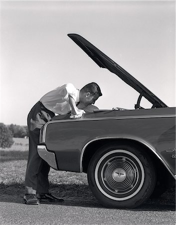 1960s SIDE VIEW OF MAN IN SHIRT & TIE LOOKING UNDER HOOD OF CAR PULLED UP ON SIDE OF ROAD Foto de stock - Con derechos protegidos, Código: 846-06112186