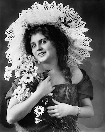 rudbéquia - 1900s 1910s TURN OF THE CENTURY WOMAN WITH LONG BRAIDS WEARING FANCY LACE HAT & HOLDING BOUQUET OF BLACK-EYED SUSAN FLOWERS Foto de stock - Direito Controlado, Número: 846-06112243