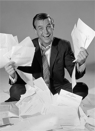 1960s HAPPY BUSINESSMAN SITTING IN A PILE OF PAPER HOLDING HANDFULS OF LETTERS BILLS INVOICES Stock Photo - Rights-Managed, Code: 846-06112398