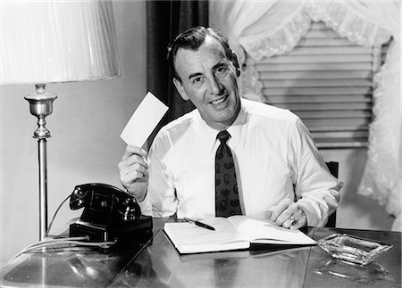 paying bill retro - 1950s MAN AT HOME DESK WRITING CHECKS SITTING BY TELEPHONE LOOKING AT CAMERA Stock Photo - Rights-Managed, Code: 846-06112494