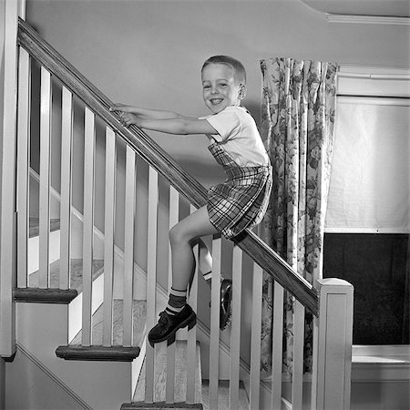 1950s SMILING YOUNG BOY SLIDING DOWN BANNISTER STAIRS STAIRCASE LOOKING AT CAMERA Stock Photo - Rights-Managed, Code: 846-07200087