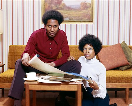 1970s AFRICAN AMERICAN MAN WOMAN COUPLE HUSBAND WIFE LOOKING AT CAMERA EXAMINING NEW HOUSE BLUEPRINTS Stock Photo - Rights-Managed, Code: 846-07760731