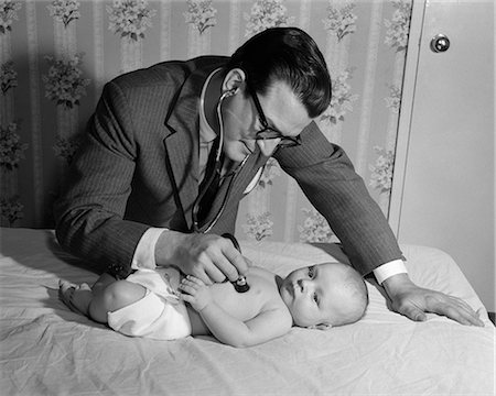 1950s DOCTOR ON HOUSE CALL HOLDING STETHOSCOPE TO HEART OF BABY LYING ON BED Photographie de stock - Rights-Managed, Code: 846-07760752