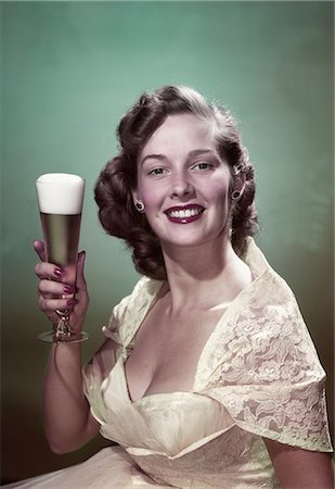 1950s PORTRAIT SMILING WOMAN WEARING FORMAL GOWN HOLDING PILSNER GLASS OF BEER LOOKING AT CAMERA Foto de stock - Con derechos protegidos, Código: 846-08030411