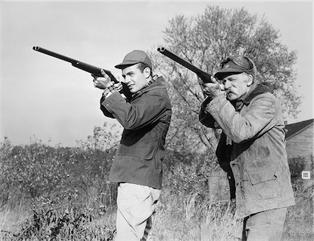 simsearch:400-04749578,k - 1940s 1950s MEN YOUNG SENIOR WITH SHOT GUNS AIMING TOWARDS CAMERA WEARING HUNTING CLOTHES & HATS Foto de stock - Con derechos protegidos, Código: 846-08140041