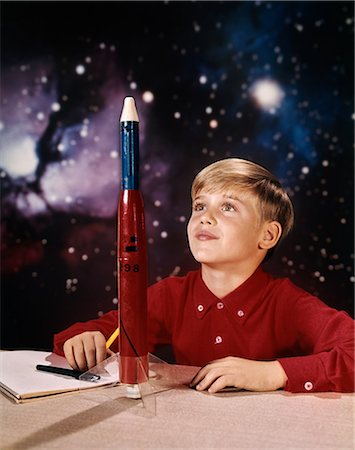 1960s BOY WITH MODEL ROCKET DAYDREAMING LOOKING AT ROCKET ON DESK STAR GALAXY BACKGROUND Photographie de stock - Rights-Managed, Code: 846-08140065