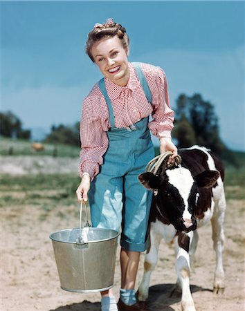 farmer with overalls - 1940s SMILING BLONDE WOMAN WEARING CHECKED SHIRT DENIM OVERALLS HOLDING PAIL WALKING CALF ON FARM Stock Photo - Rights-Managed, Code: 846-08140088