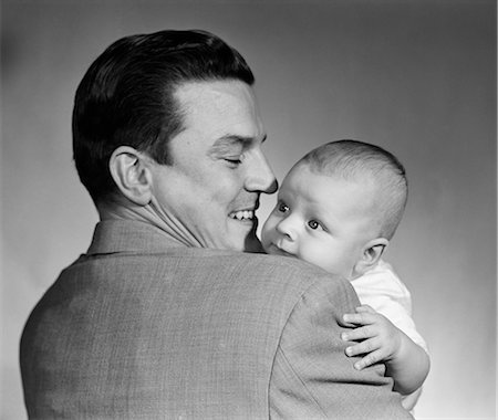 simsearch:846-08512704,k - 1950s PROUD SMILING MAN FATHER BACK TOWARD CAMERA HOLDING BABY SON FACE TO CAMERA Stockbilder - Lizenzpflichtiges, Bildnummer: 846-08226065