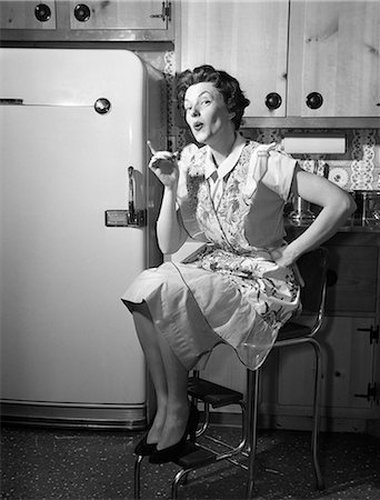 1950s HOUSEWIFE SITTING ON STOOL IN KITCHEN POINTING FINGER LOOKING AT CAMERA Foto de stock - Con derechos protegidos, Código: 846-08226098